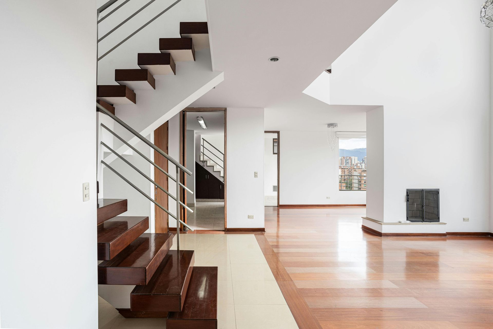Aerial view of a cleared dirt area in a grassy field, trees in the background, blue sky.
