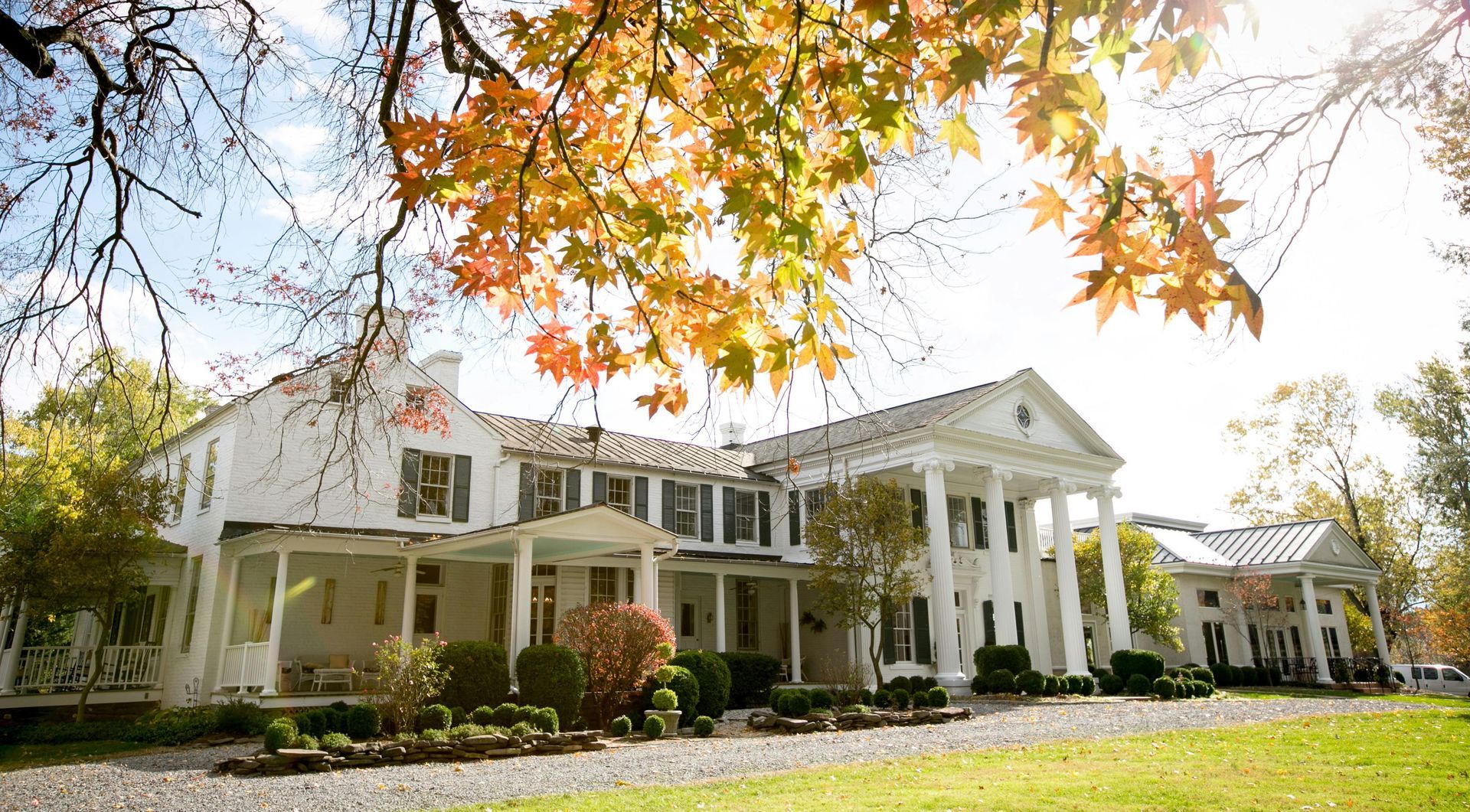 White colonial home with front porch and fall trees