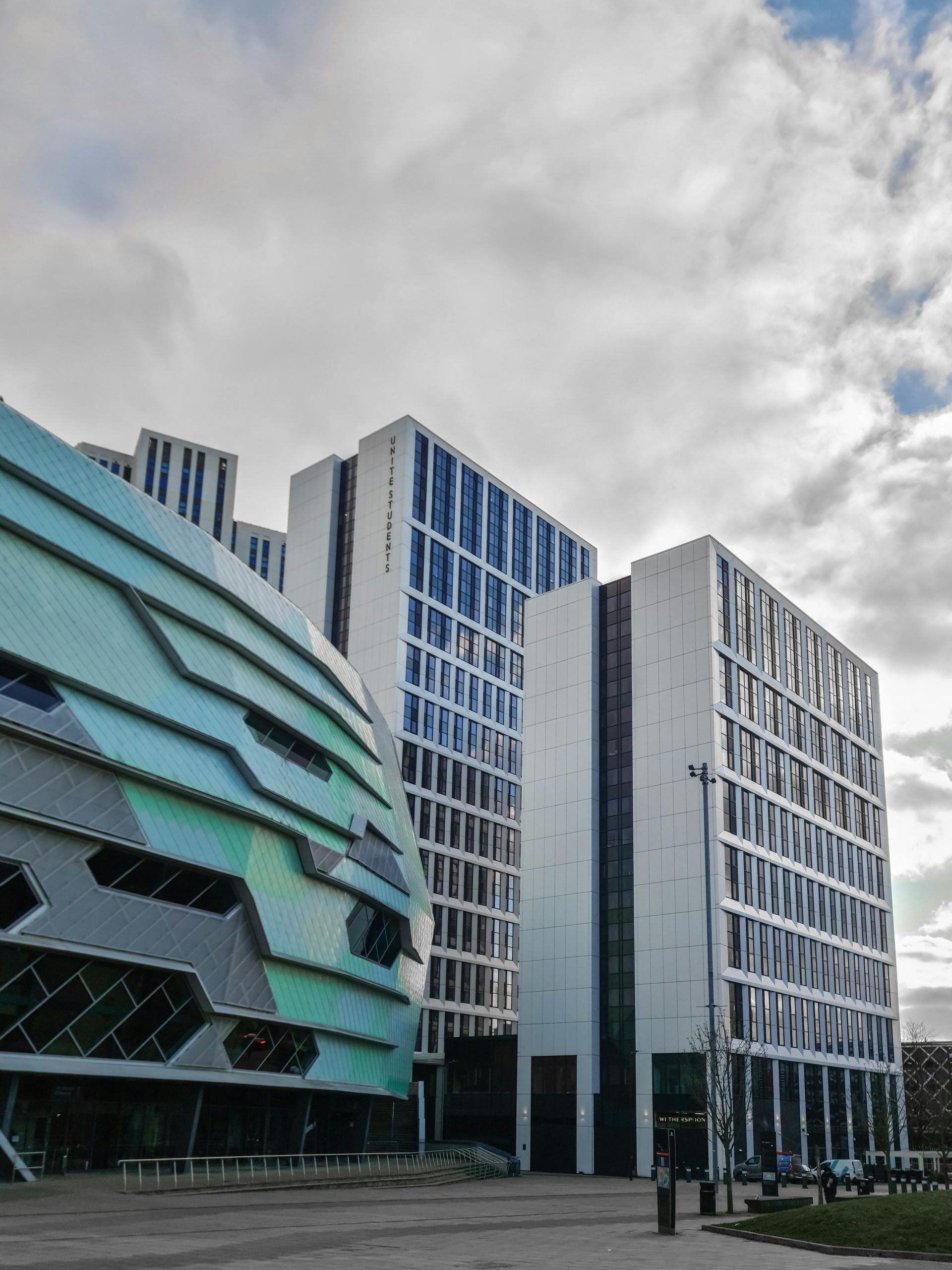 Downtown street view at sunset, buildings line road, cars parked along side.