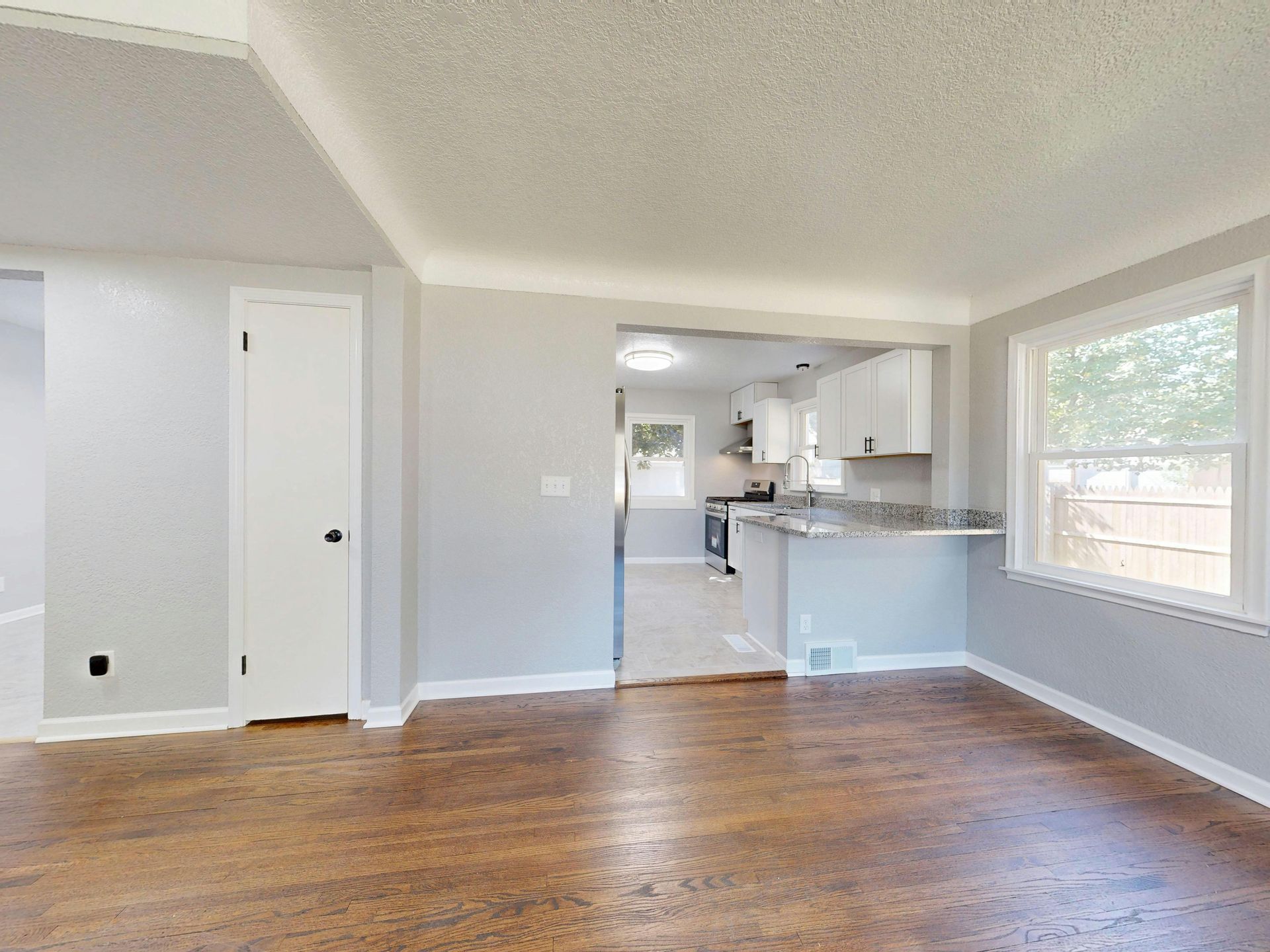 Aerial view of new houses along a paved road, surrounded by green grass and construction areas.