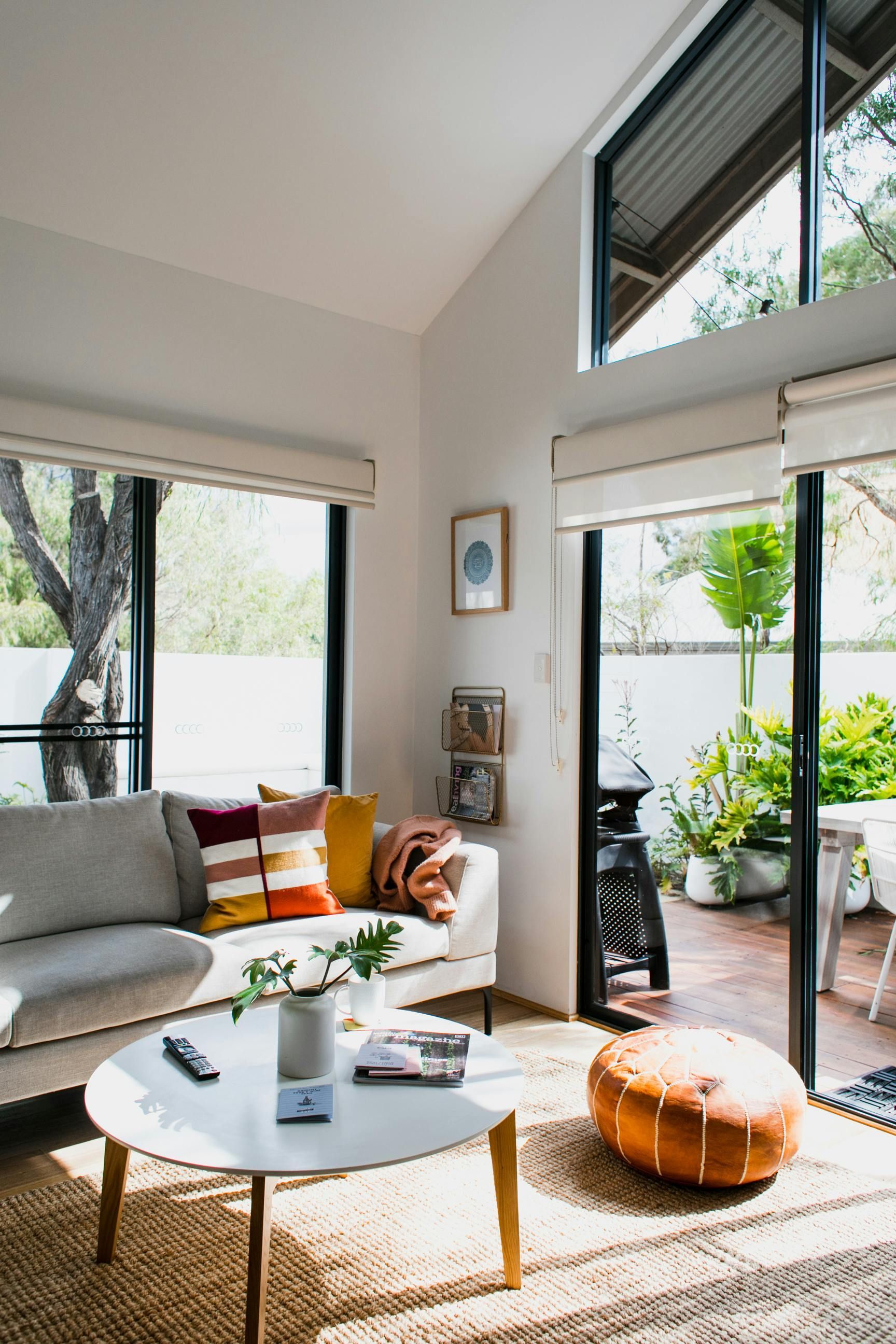 Living room with a sofa, coffee table, and open door to a patio with plants.