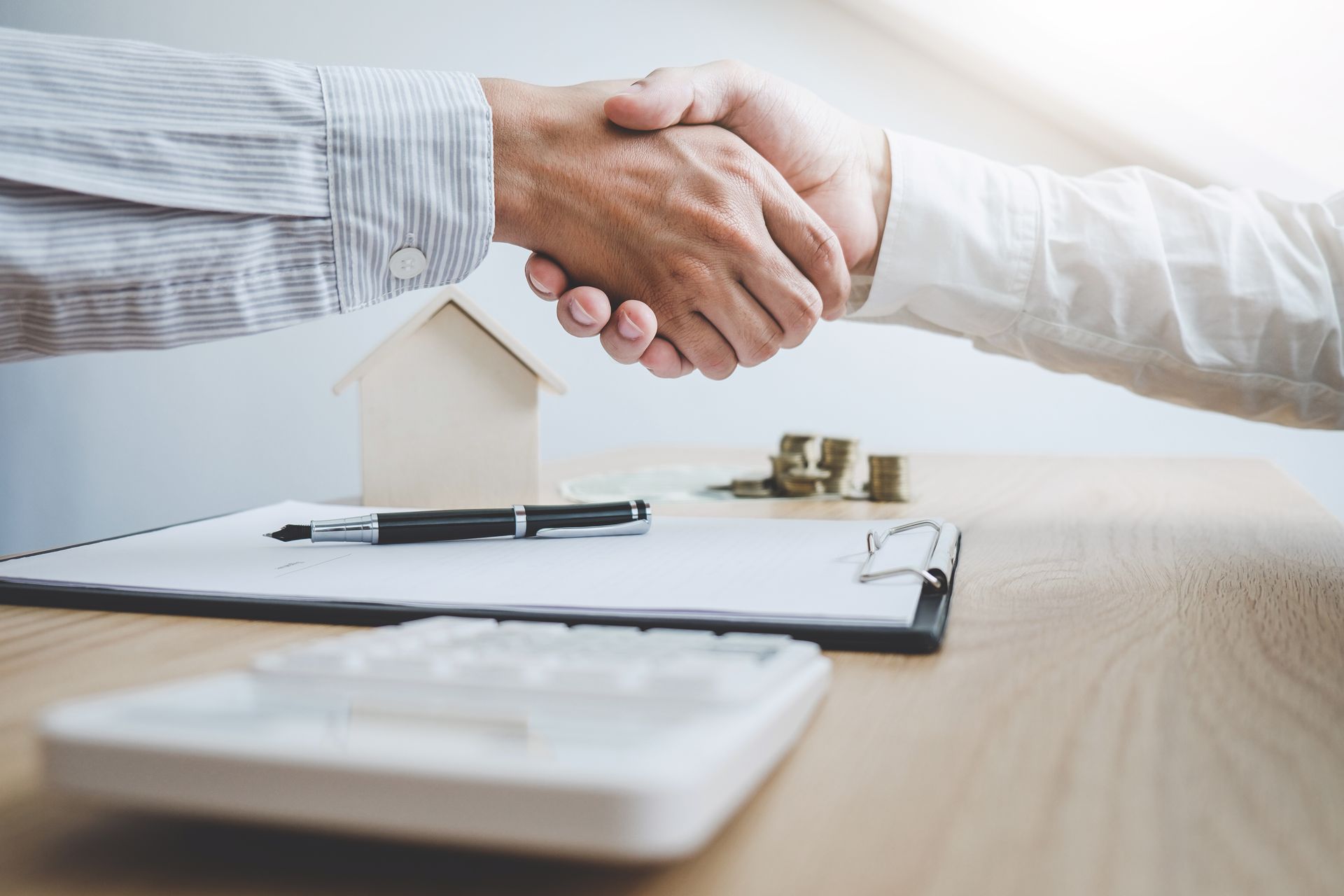 Seller and real estate agent shaking hands over home sale documents