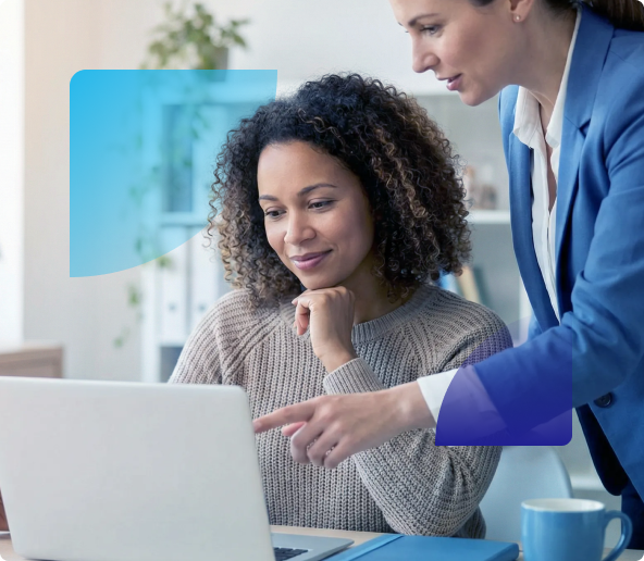 Two colleagues reviewing a laptop together in a bright office, one pointing at the screen.