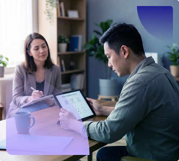 Two people in a meeting, one using a tablet while the other takes notes at a table.