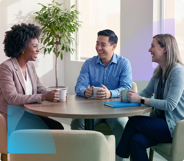 Three people talking around a round table in a bright office lounge