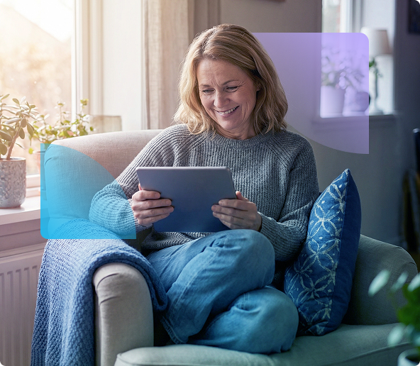 Woman smiling on a sofa, using a tablet in a bright living room