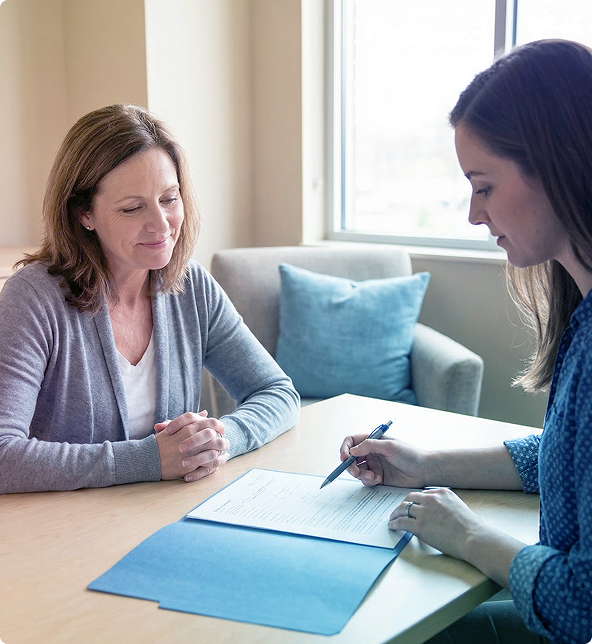 Two people review a document at a table in a bright office, with one taking notes.