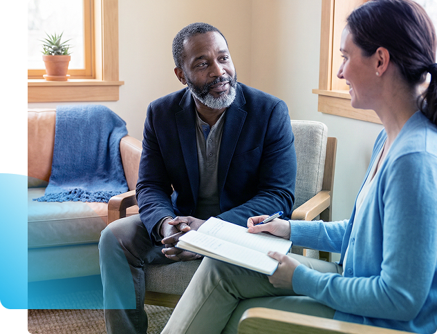 Two people talking on a couch while reviewing notes in a bright living room