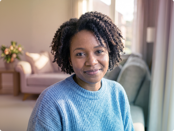 Two people talking on a couch with notebooks and a coffee cup in a bright living room.