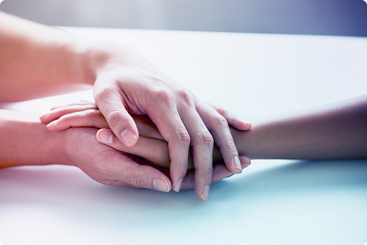 Two hands gently clasped on a bright surface