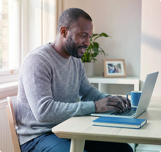 Person typing on a laptop at a desk in a bright home office