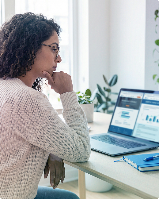 Person working on a laptop at a bright desk, reviewing charts on the screen