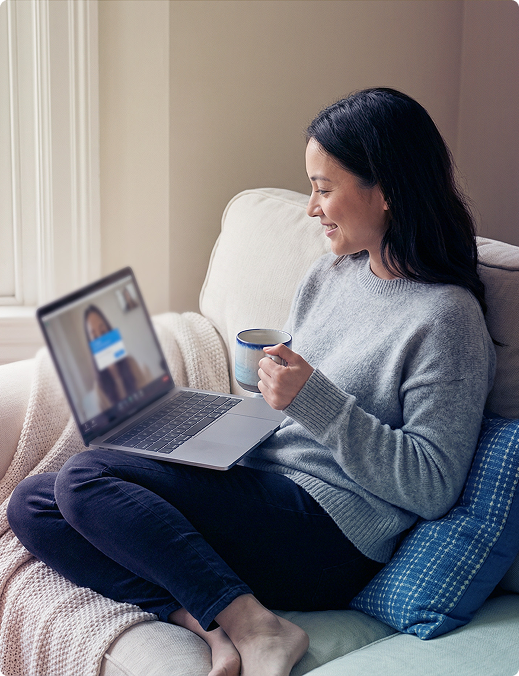 Woman sitting on a couch using a laptop in a bright living room