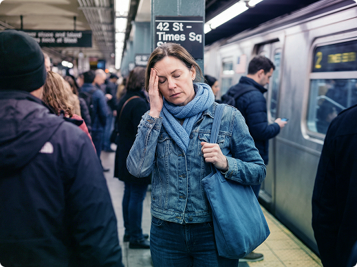 Man sitting on a sofa by a window, smiling in conversation with someone off-frame, with a notebook on the table.