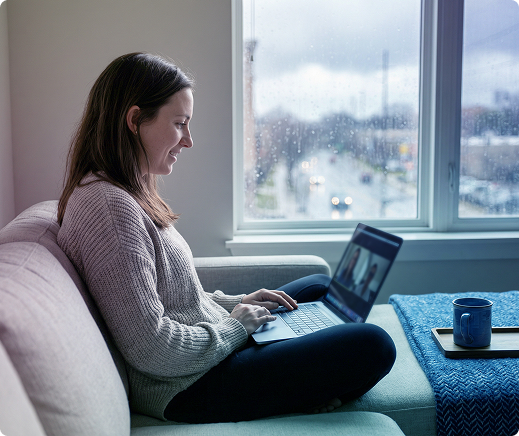 Woman sitting on a couch using a laptop in a bright living room