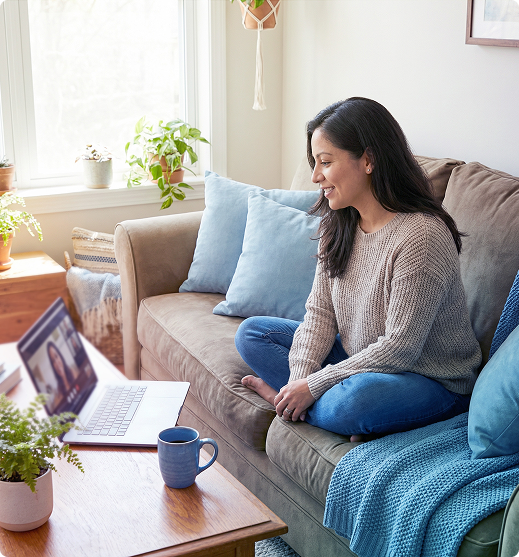 Woman sitting on a couch using a laptop in a bright living room