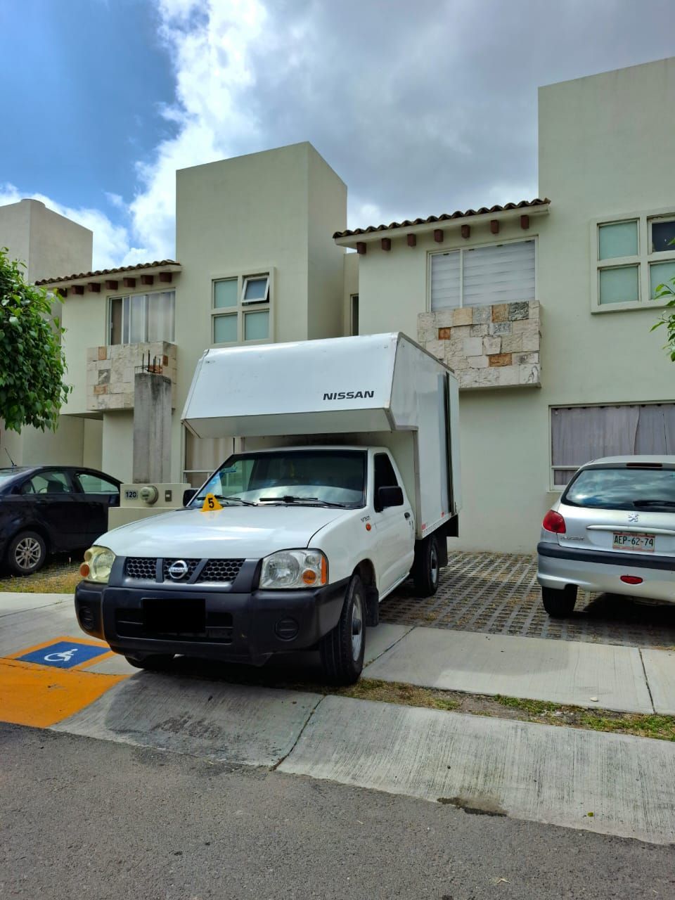 Una camioneta Nissan blanca está estacionada frente a una casa.