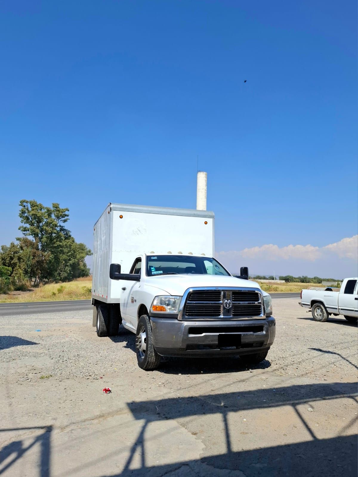Un camión blanco con una caja en la parte trasera está estacionado en un estacionamiento.