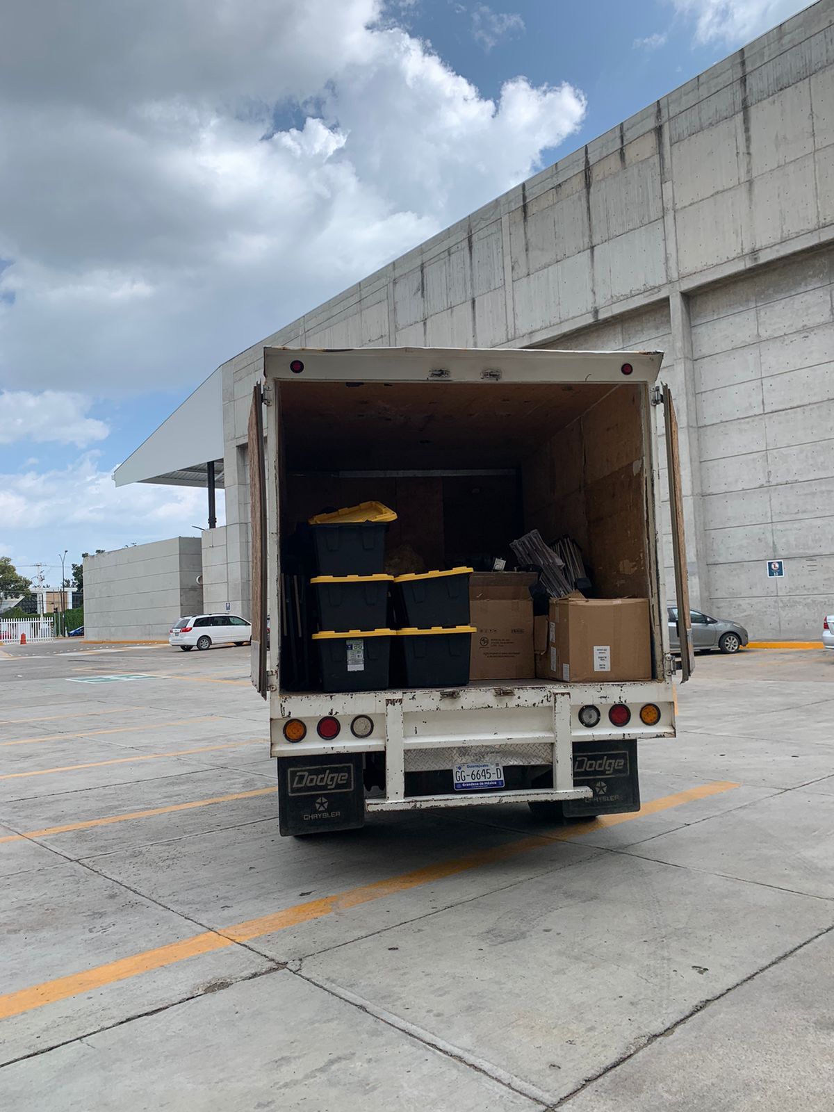 Un camión blanco está estacionado en un estacionamiento con la puerta trasera abierta.