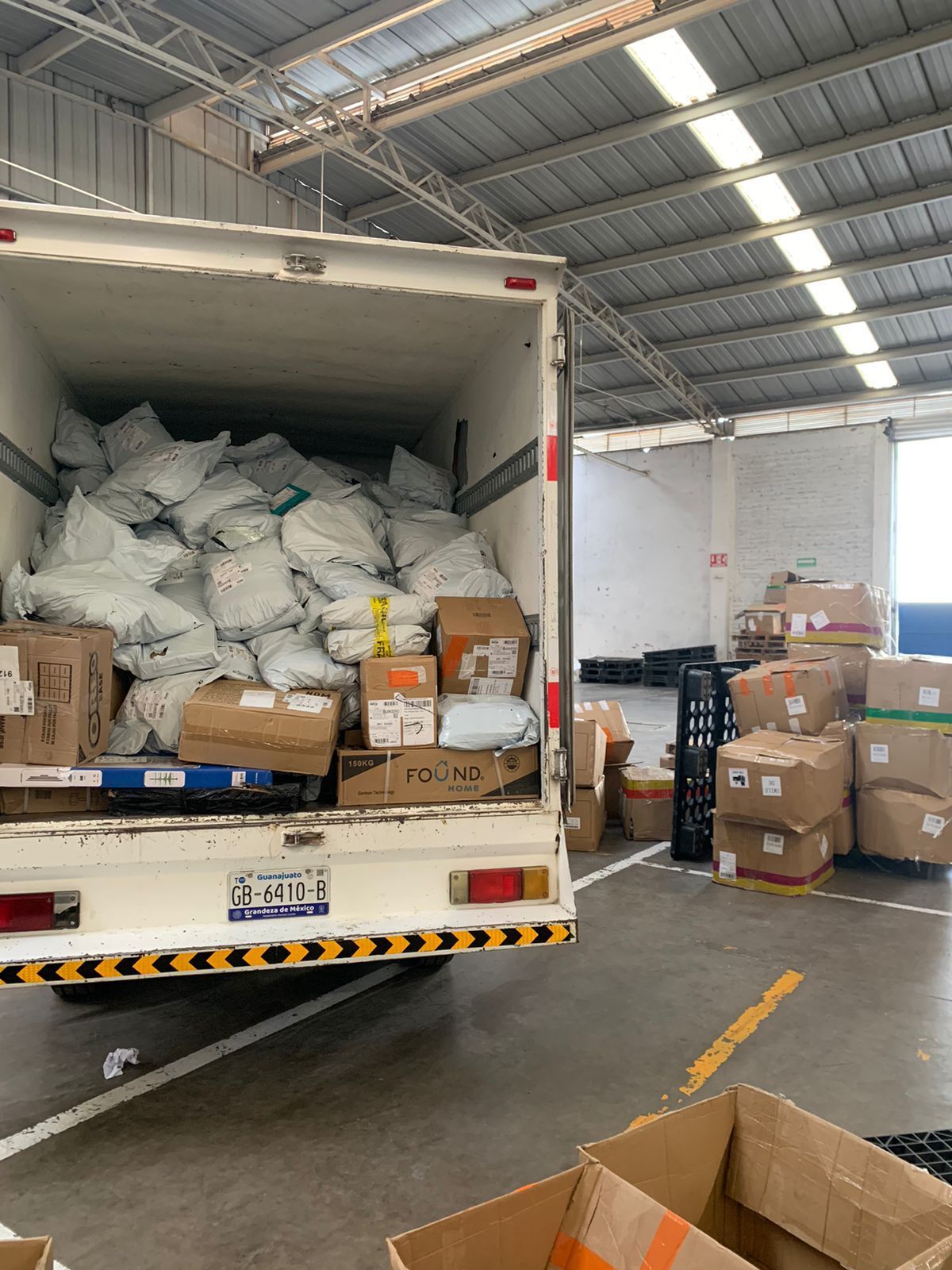 Un camión está lleno de cajas y bolsas en un almacén.