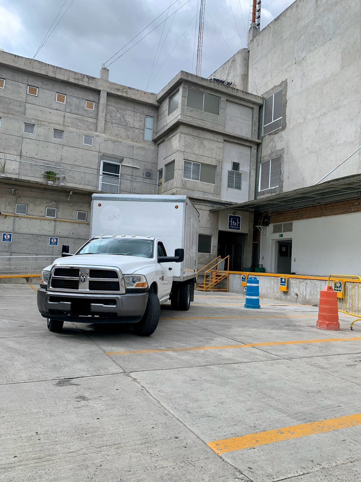 Un camión blanco está estacionado en un estacionamiento frente a un edificio.