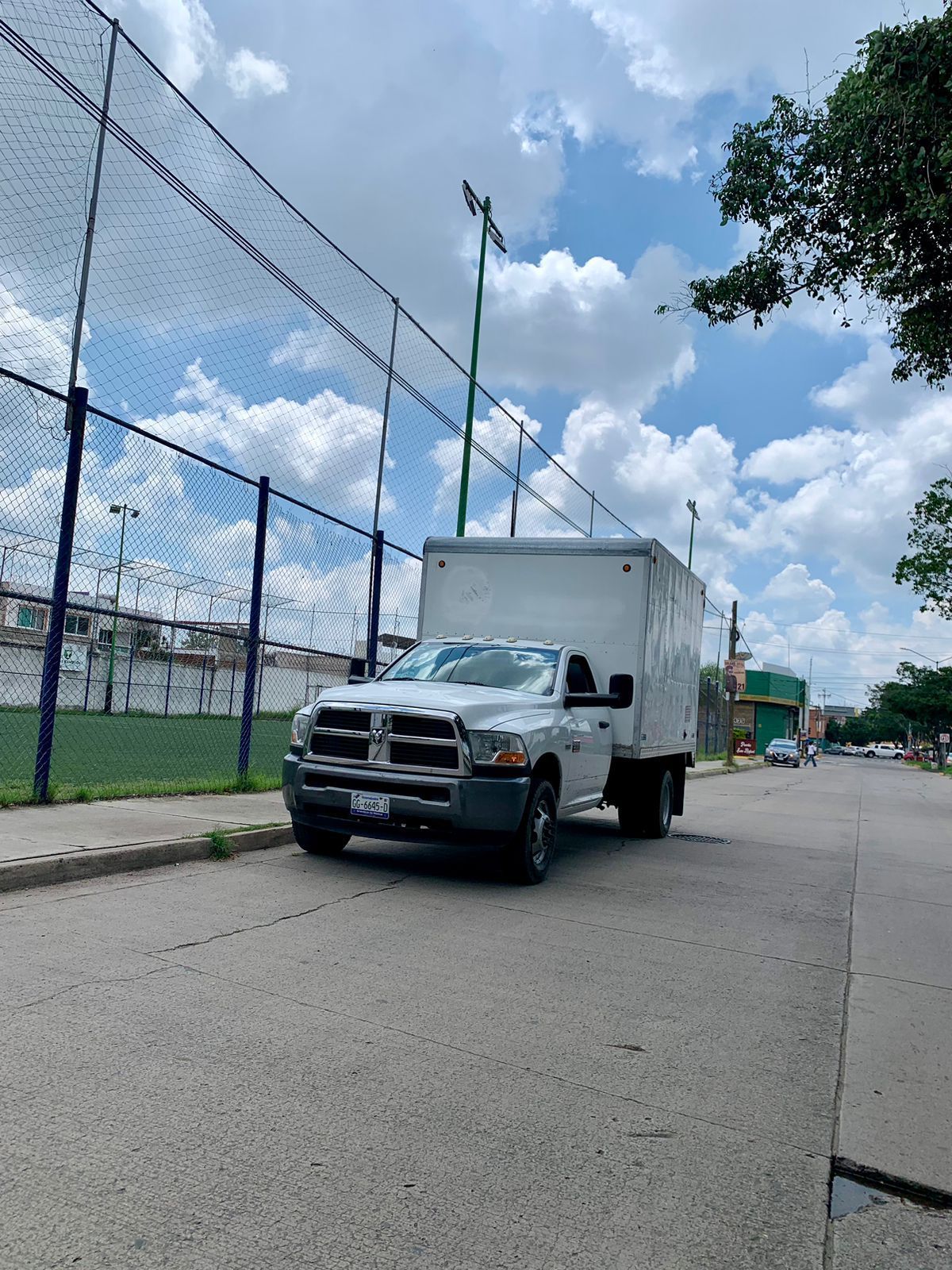 Un camión blanco está estacionado al costado de la carretera al lado de una valla.