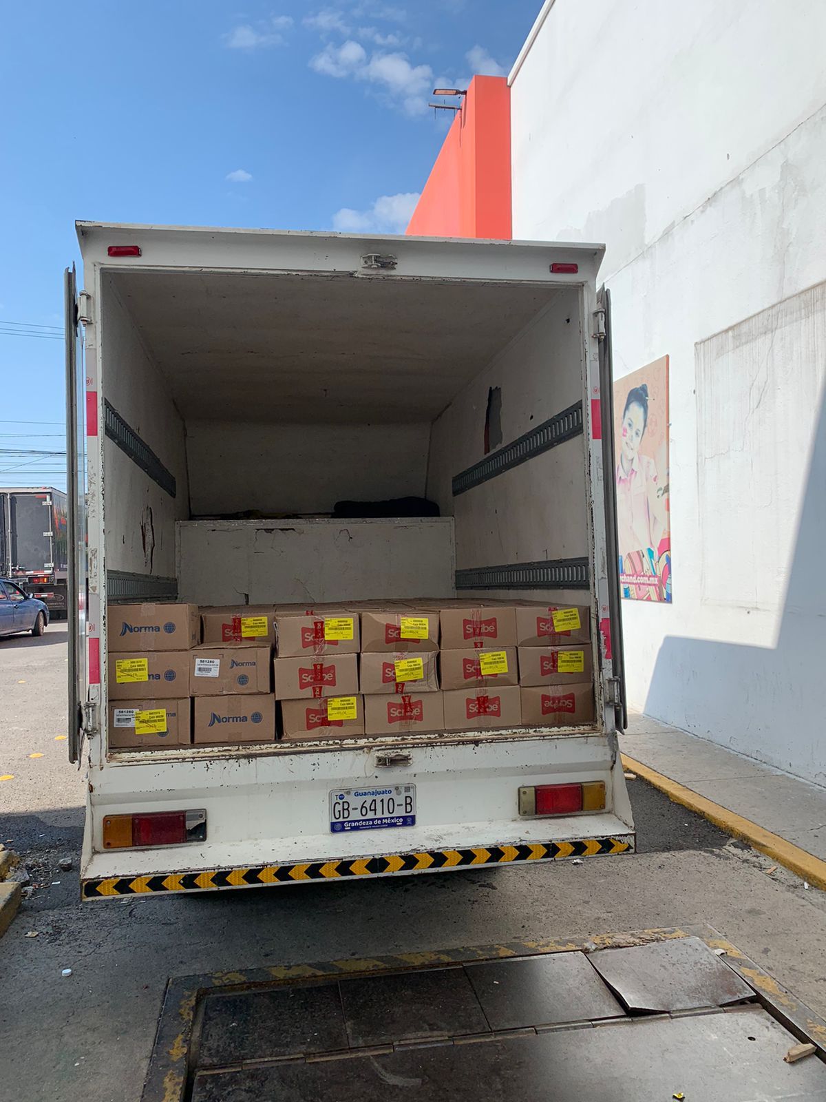 Un camión blanco con cajas en la parte trasera está estacionado en un estacionamiento.