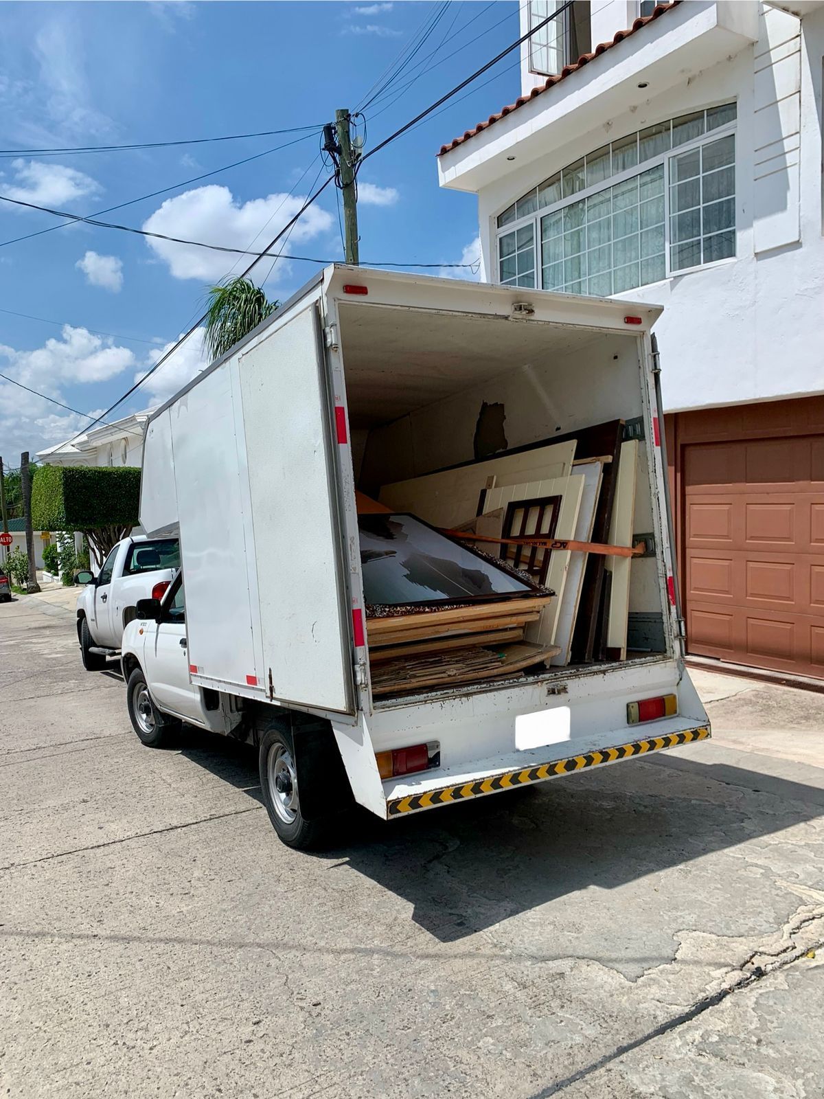Un camión blanco está estacionado al costado de la carretera al lado de una casa.