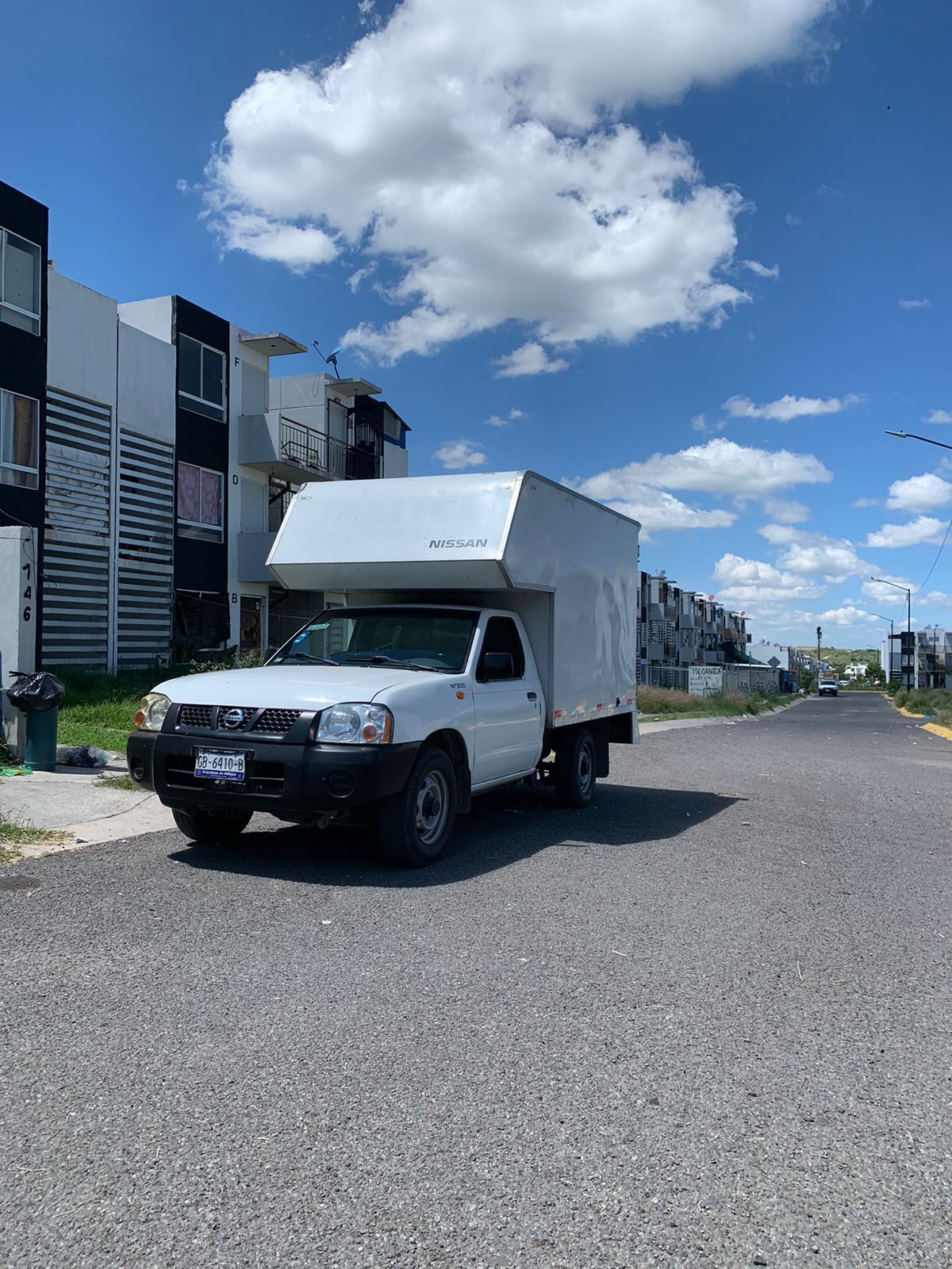 Un camión blanco está estacionado al costado de la carretera en una zona residencial.