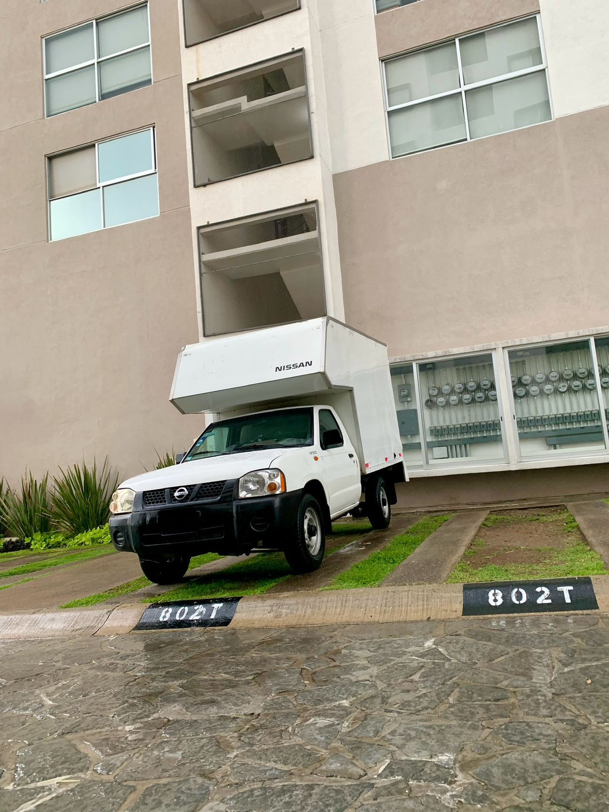 Un camión blanco está estacionado frente a un edificio.