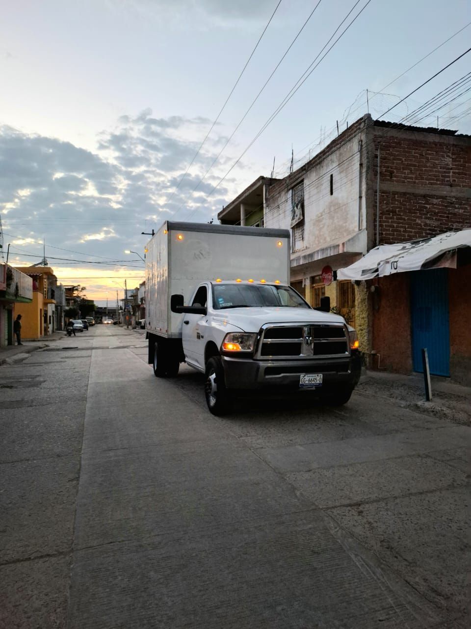 Un camión blanco circula por una calle al lado de un edificio.