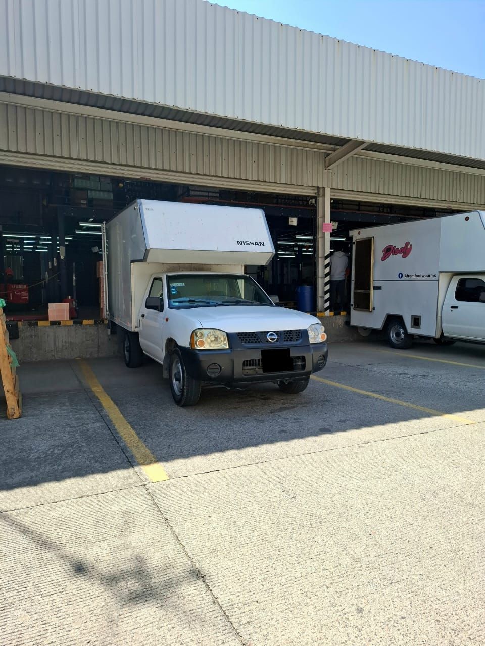 Un camión blanco está estacionado en un estacionamiento frente a un edificio.