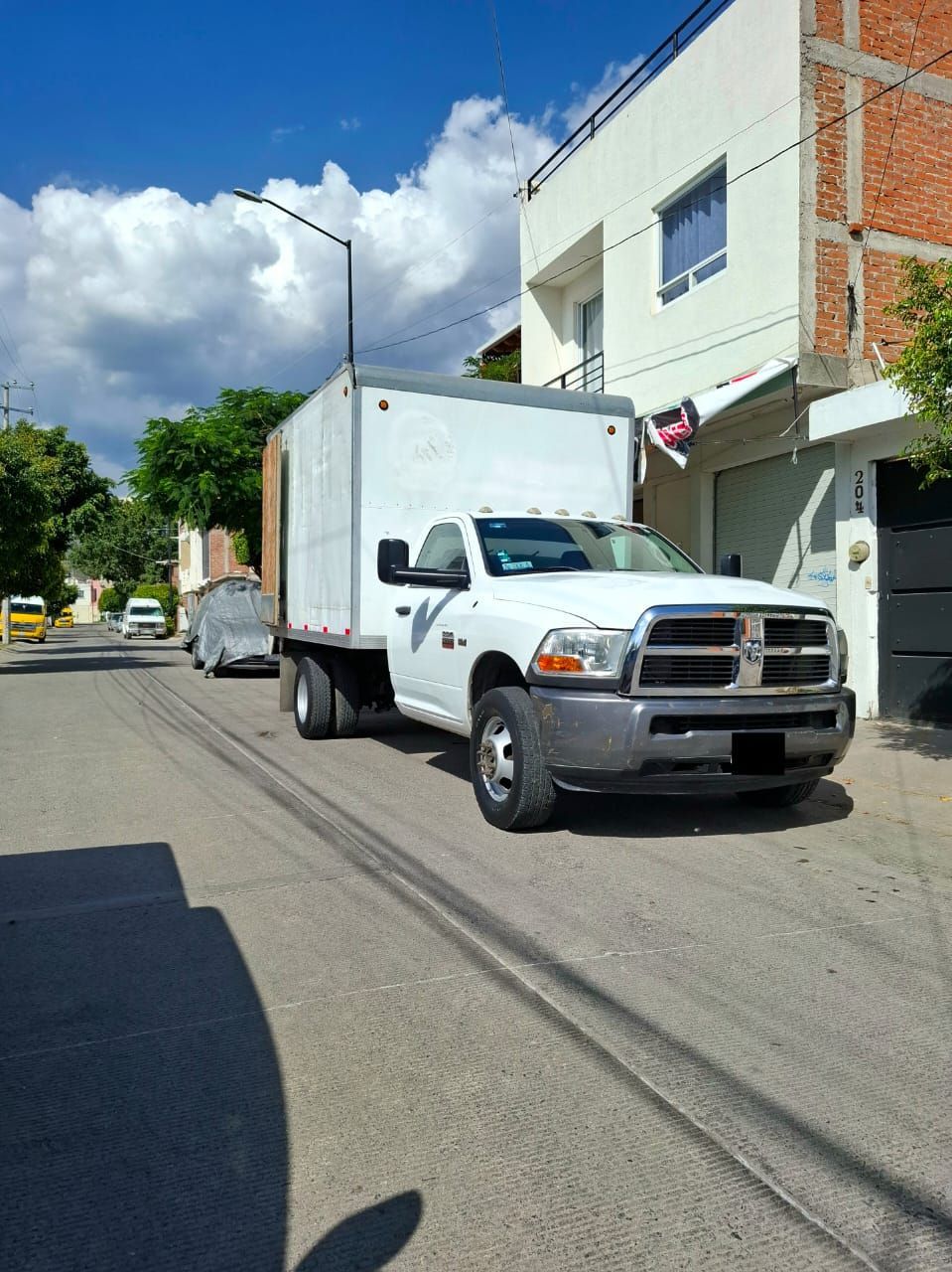 Un camión blanco está estacionado al costado de la carretera frente a un edificio.