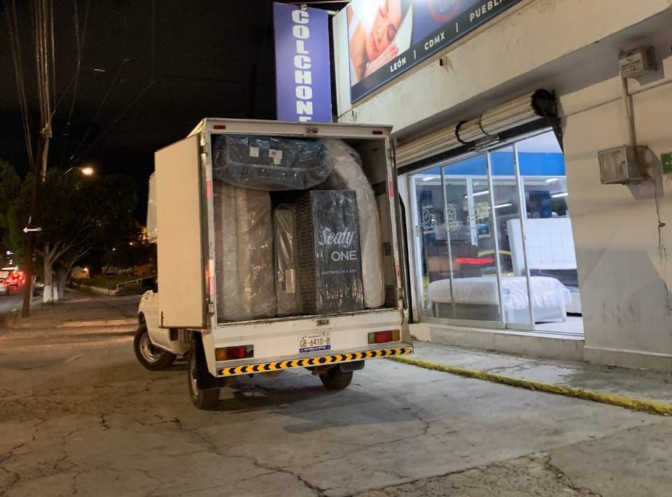 Un camión blanco está estacionado frente a una tienda por la noche.