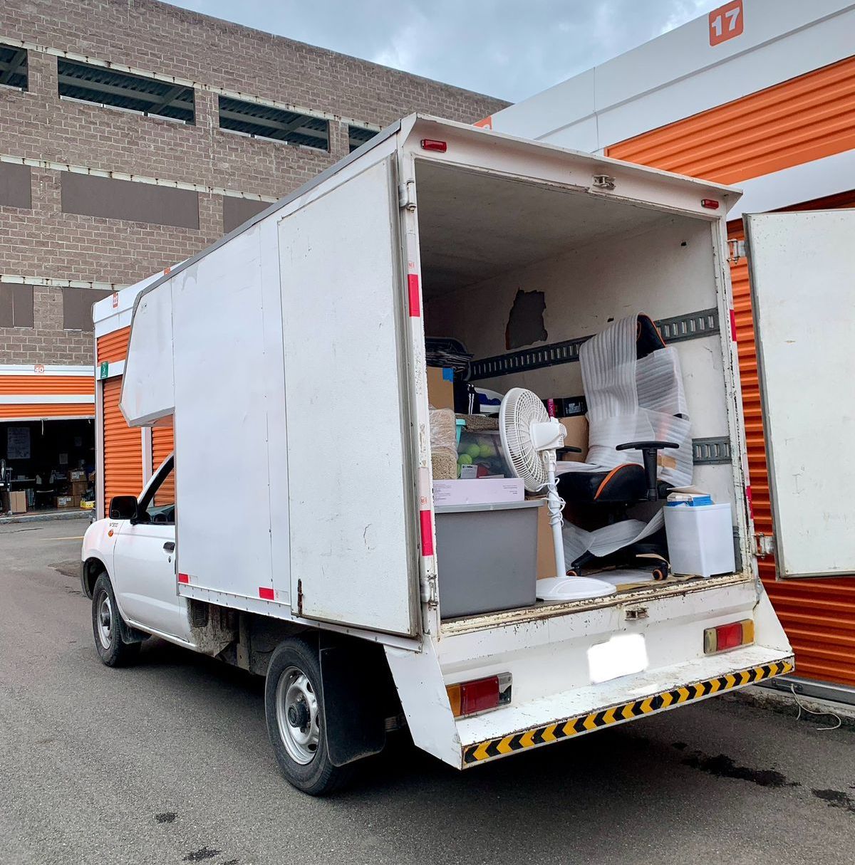 Un camión blanco está estacionado frente a un edificio con la puerta abierta.