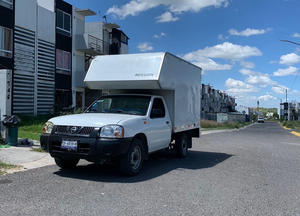 Un camión blanco está estacionado al costado de la carretera.