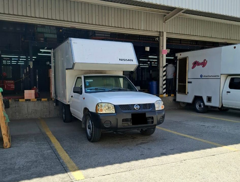 Un camión blanco está estacionado en un estacionamiento frente a un edificio.