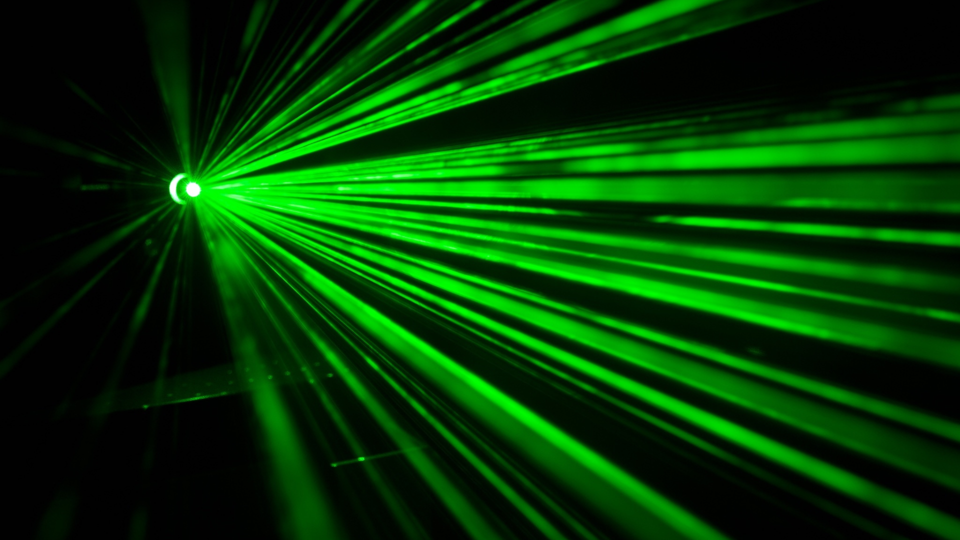 A green laser beam is shining on a black background.