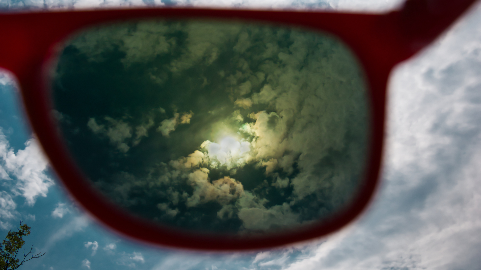 The sun is reflected in the lenses of a pair of sunglasses.