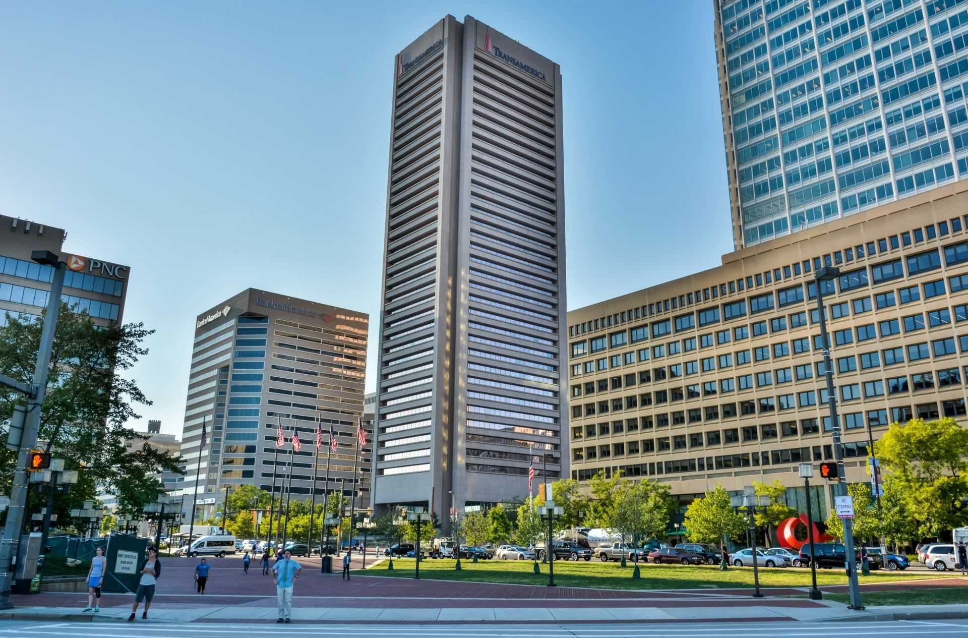 Buildings in downtown Baltimore: tall office tower, other buildings, trees, blue sky.