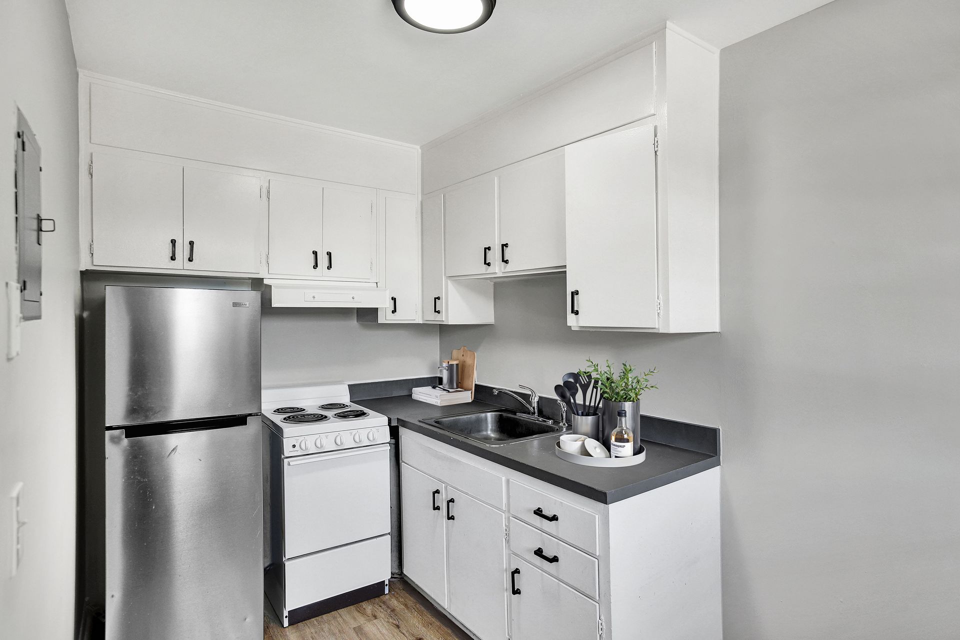 White kitchen with refrigerator, cabinets, granite countertops, and stove.