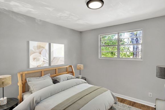 Bedroom with bed, art, window, and lamps; gray walls and white ceiling.
