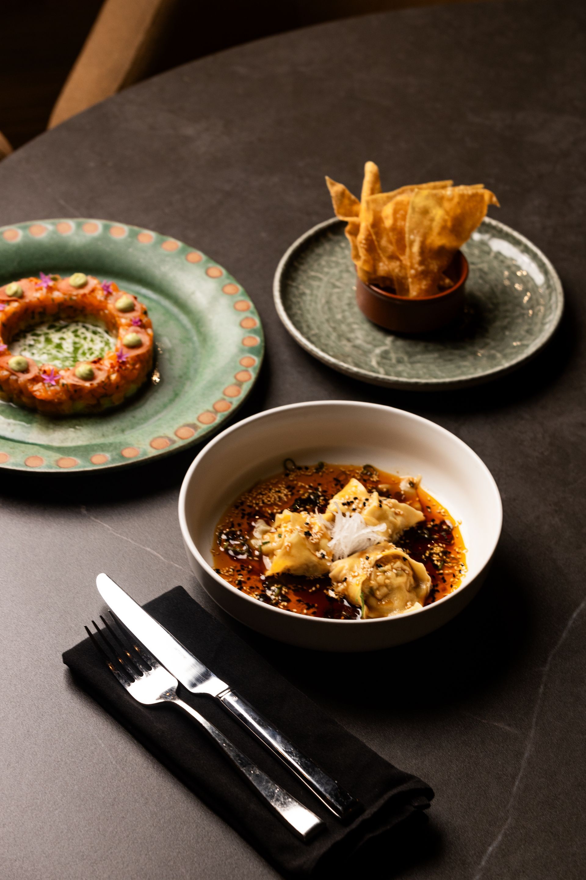 A table topped with three plates of food and a bowl of food.
