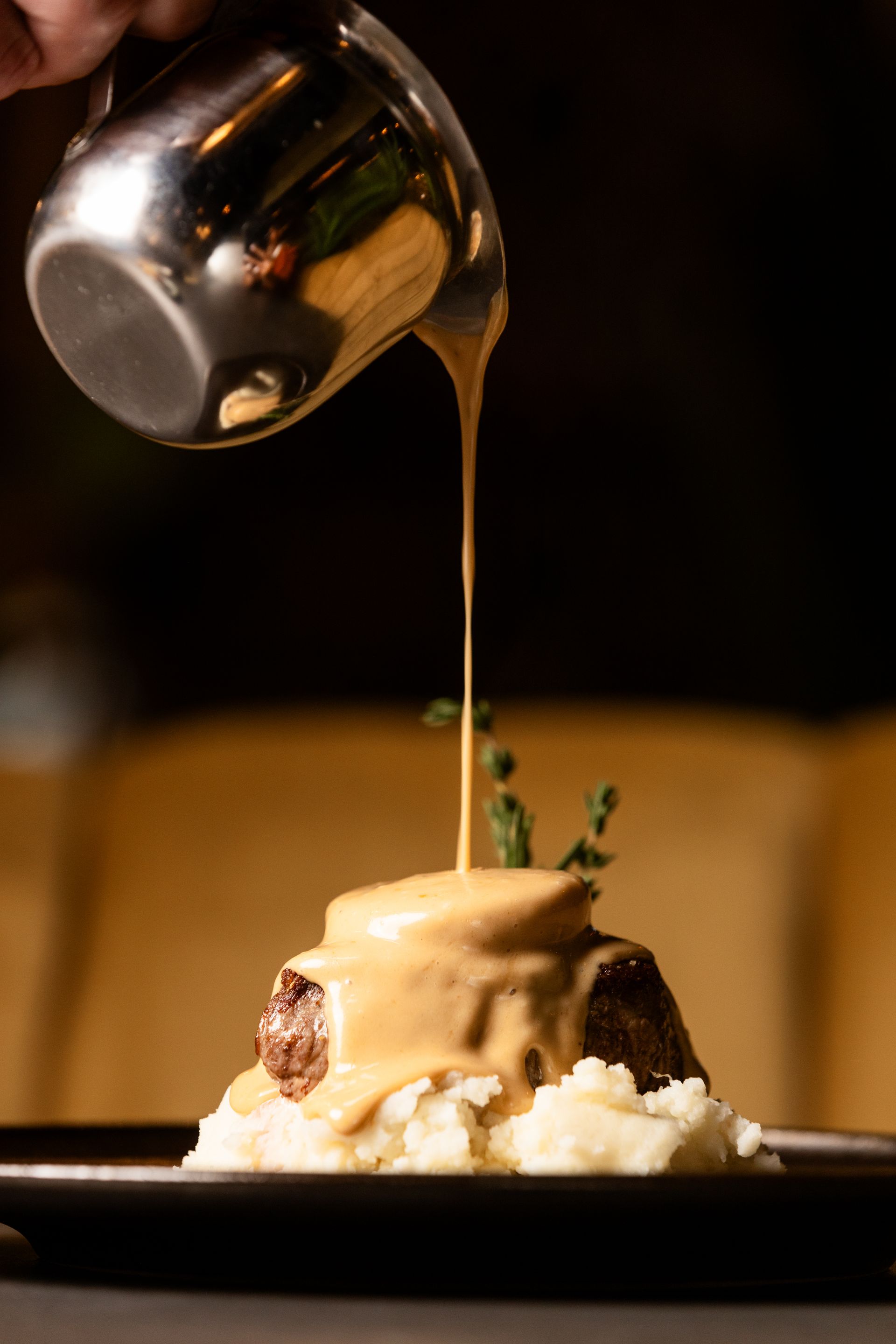 A person is pouring gravy on a plate of food.