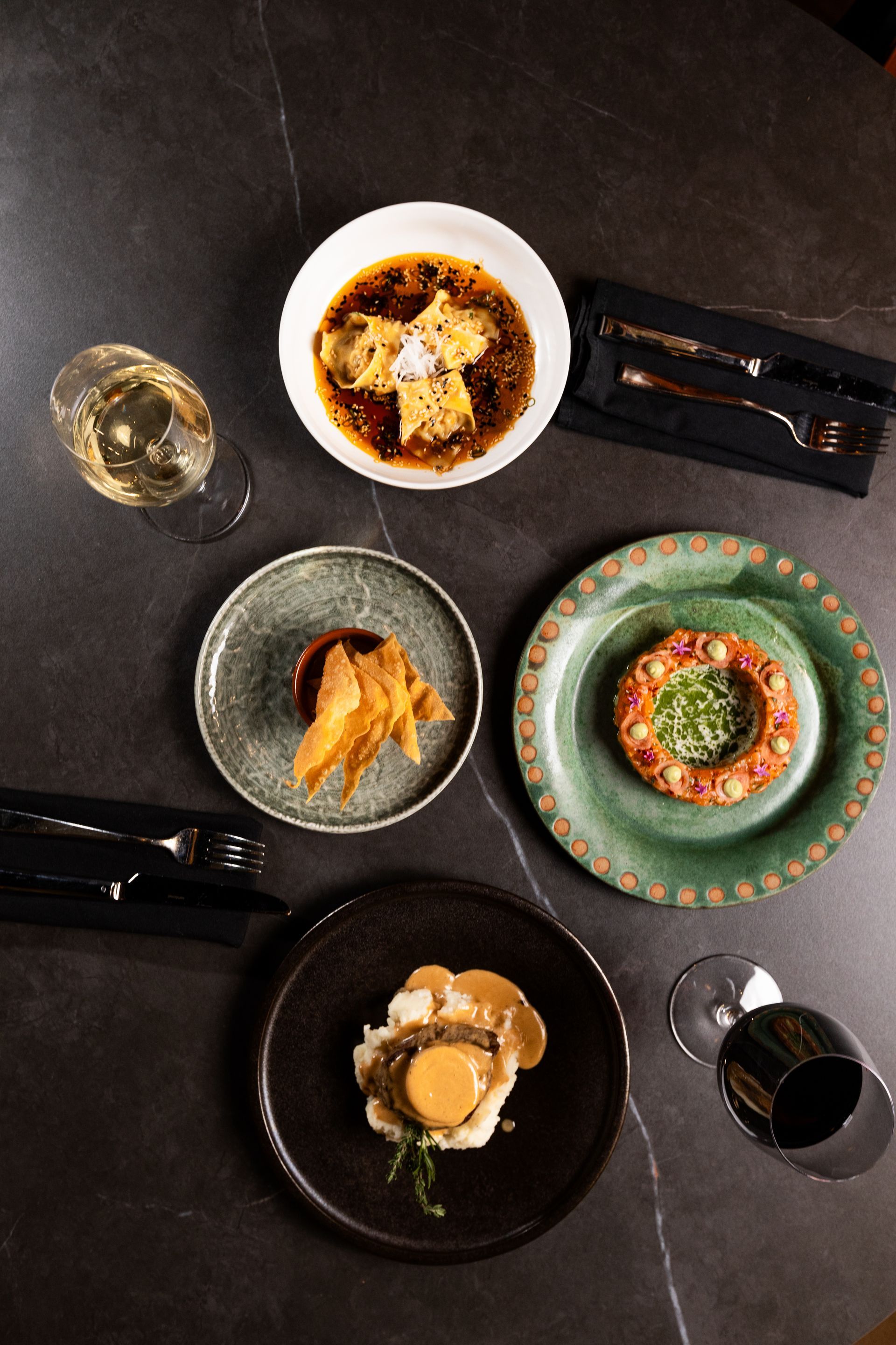 A table topped with plates of food and wine glasses.