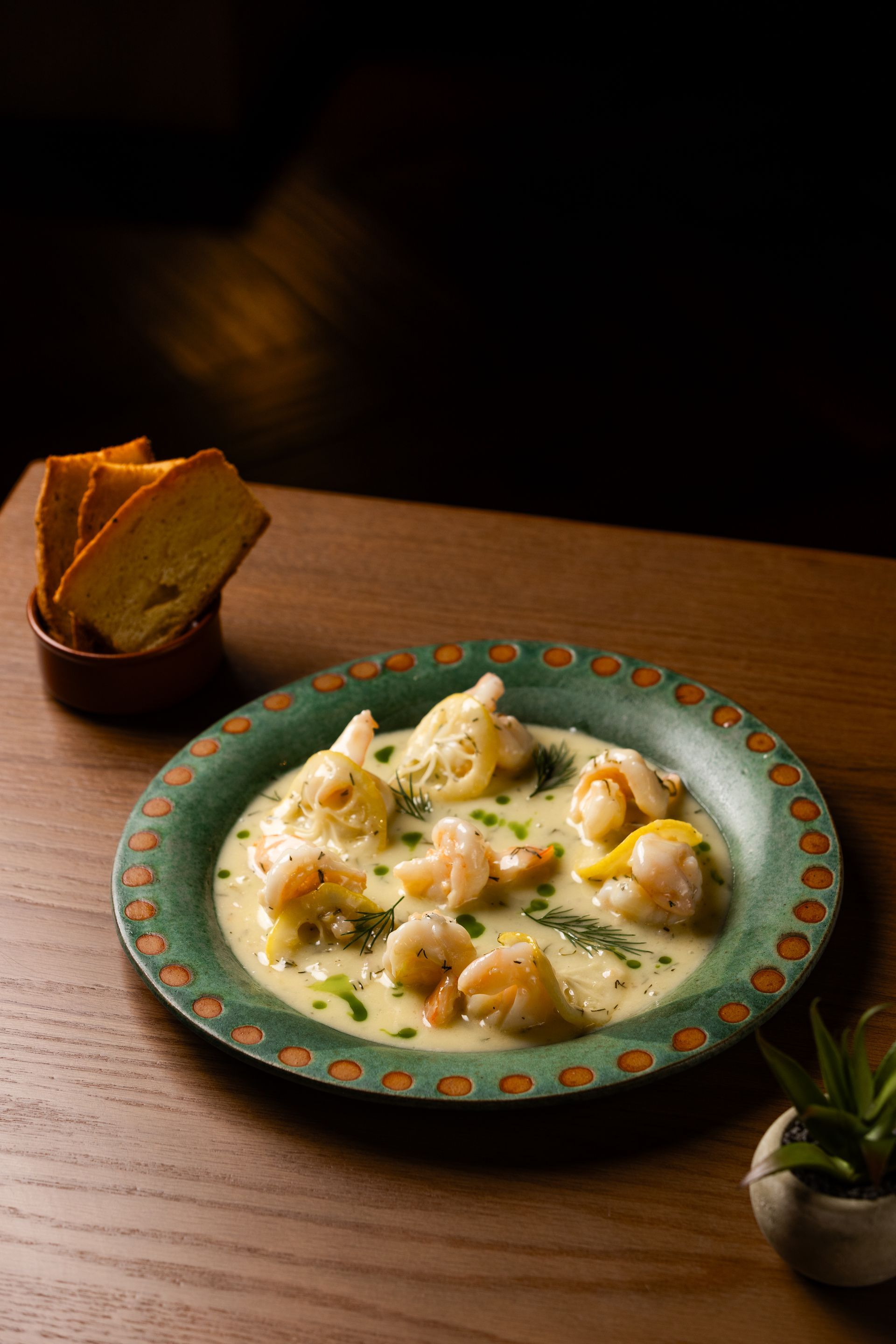 A plate of food with shrimp and bread on a wooden table.