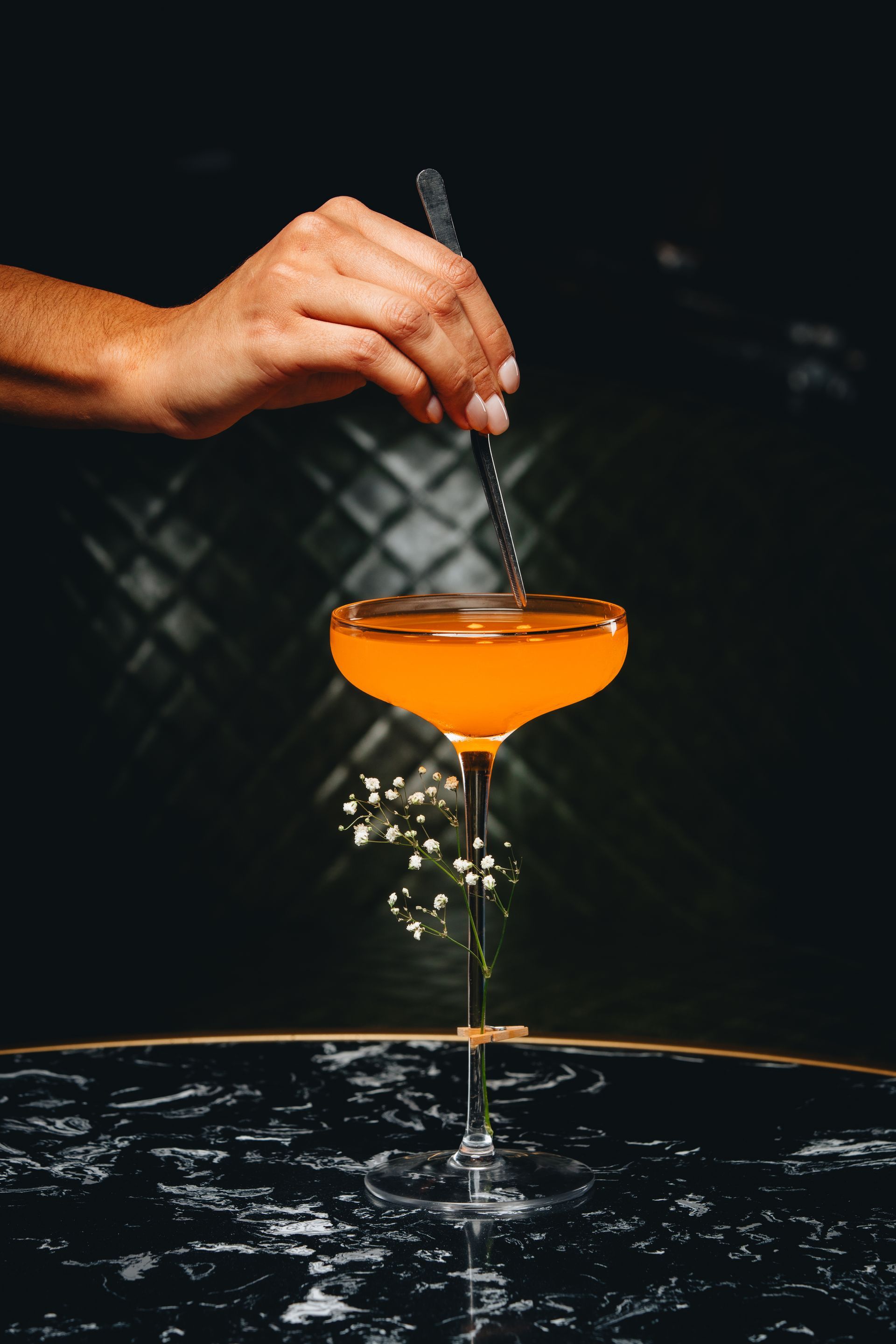 a person is stirring a cocktail in a martini glass with a spoon .