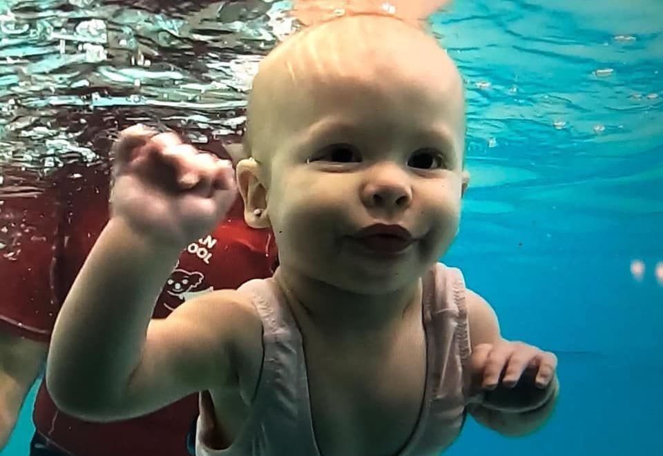 A woman is feeding a baby in a swimming pool.