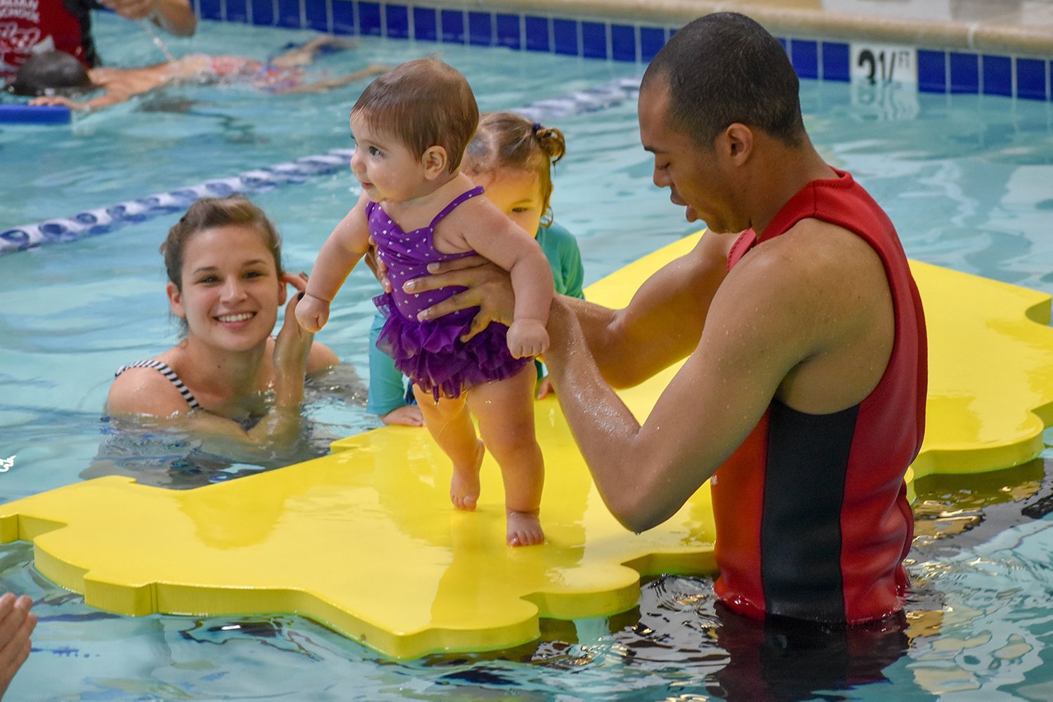 A man is holding a baby in a swimming pool.