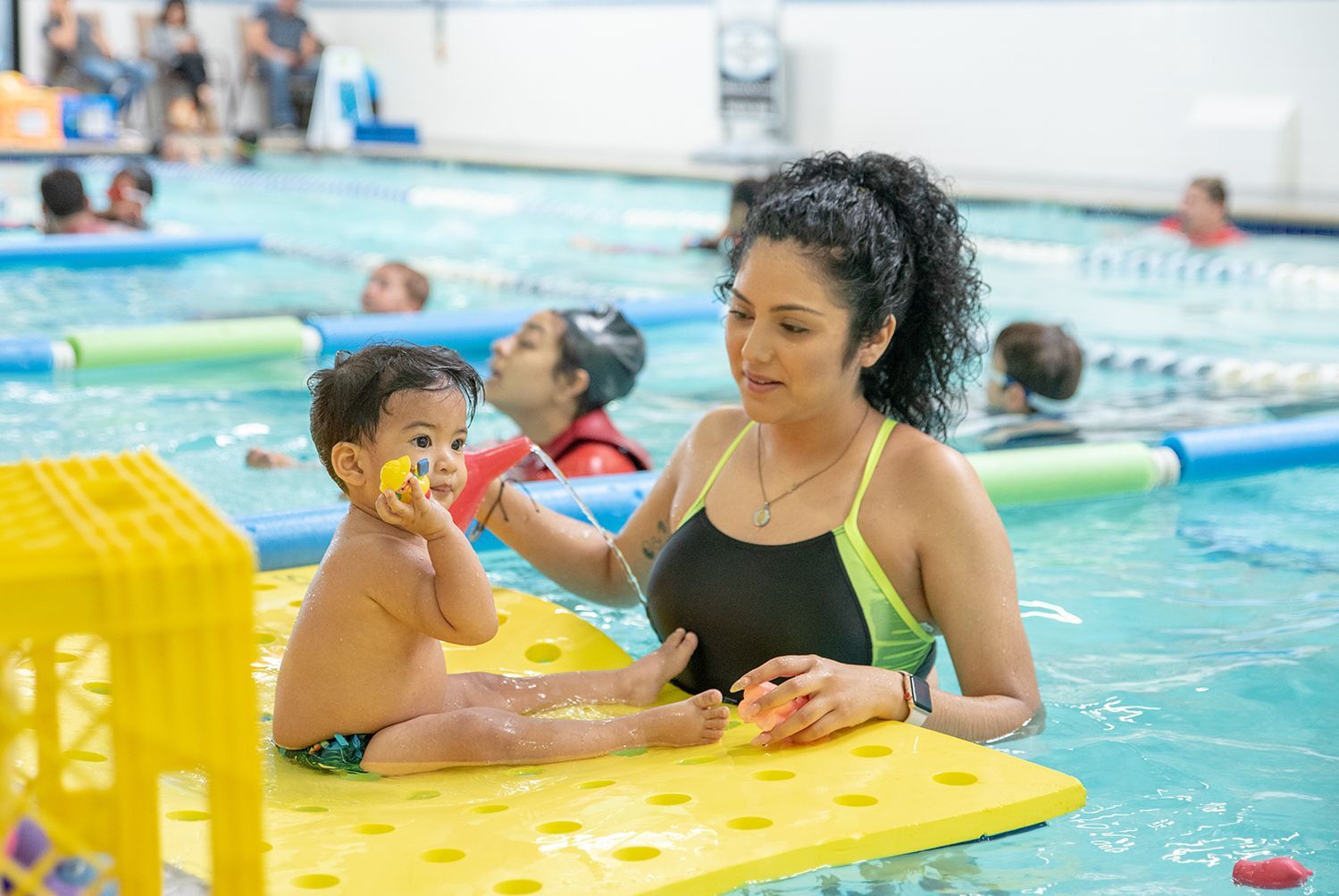 A woman is feeding a baby in a swimming pool.